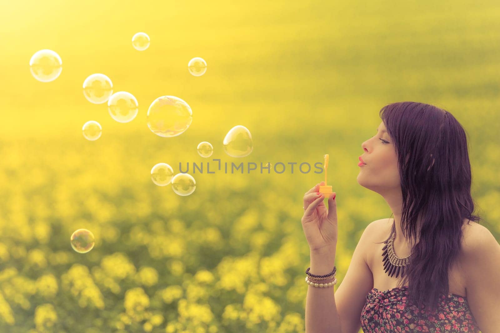 The genuine girl has fun playing in a yellow green meadow and is enjoying her youth.
