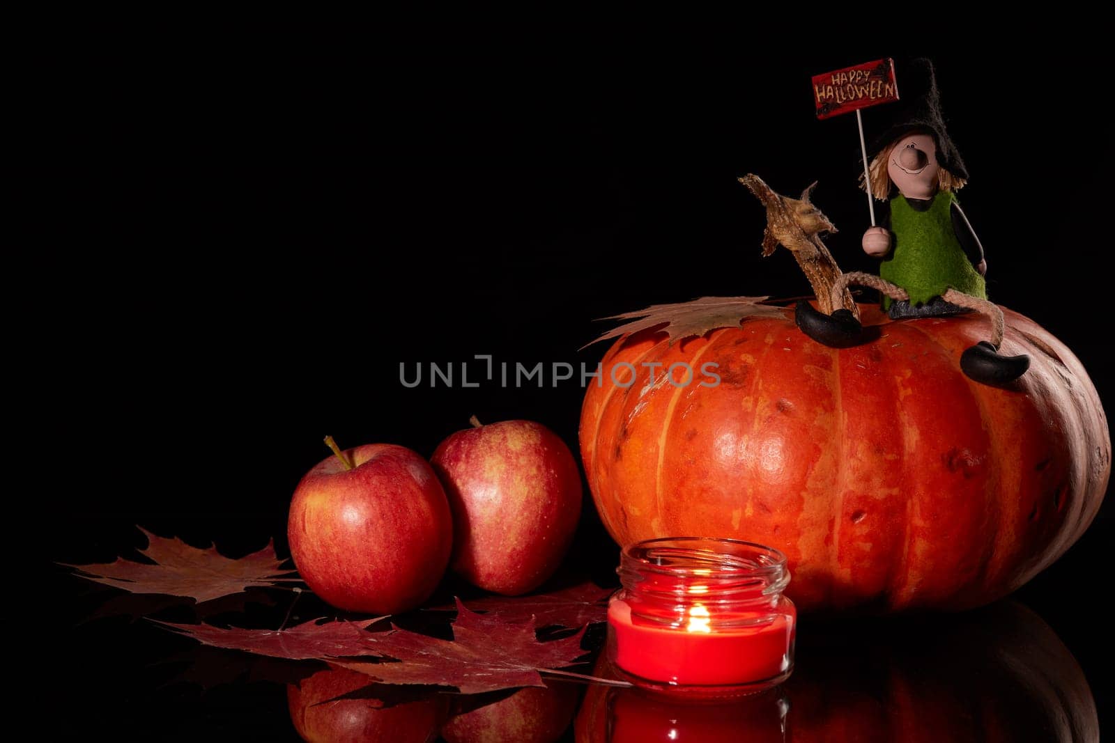 Halloween still life with pumpkin, autumn leaves, candle and witch on a black background. Halloween background