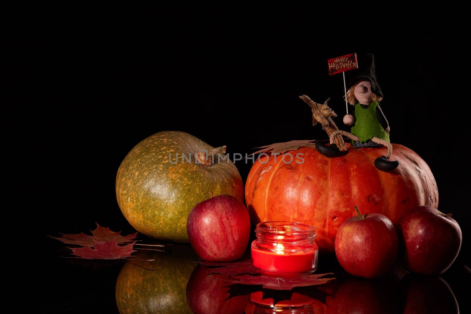 Halloween still life with pumpkin, autumn leaves, candle and witch on a black background. Halloween background