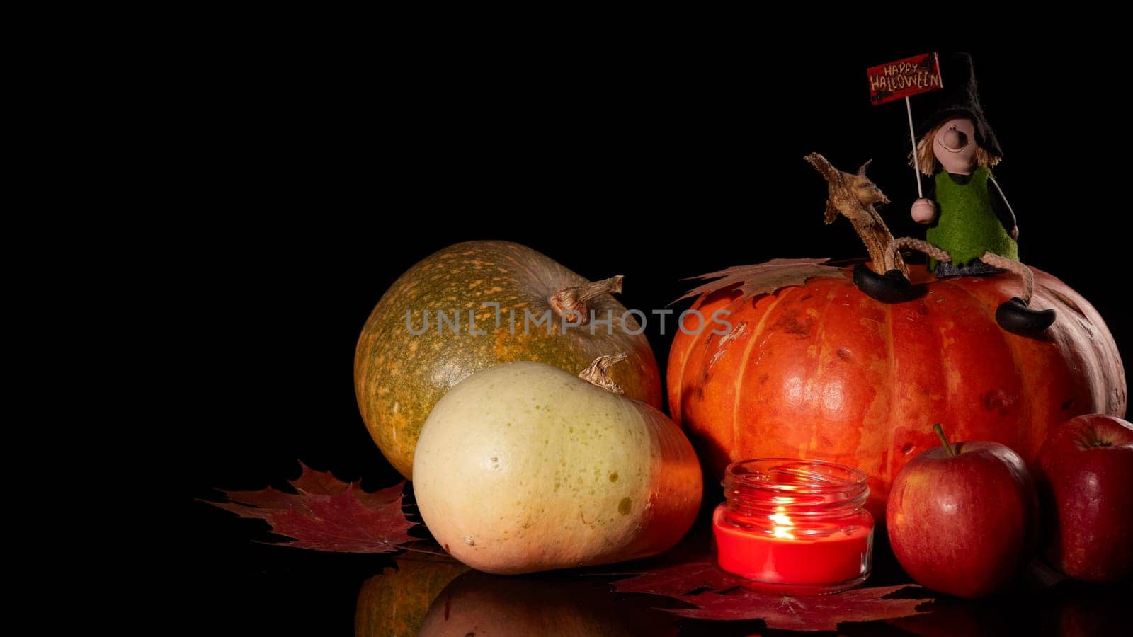 Halloween still life with pumpkin, autumn leaves, candle and witch on a black background. Halloween background