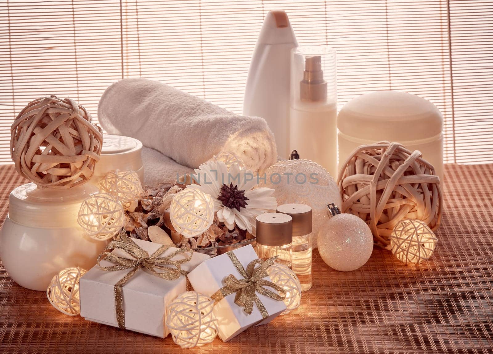 Spa still life with cosmetic creams, towel, gift boxes and Christmas ornaments standing on bamboo mat. New Year and Christmas Healthy lifestyle, body care, Spa treatment and relaxation concept
