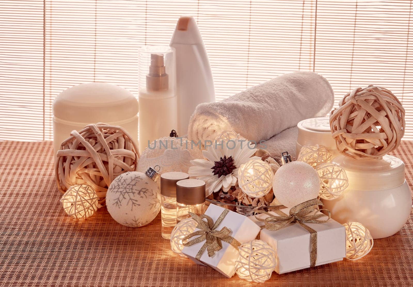 Spa still life with cosmetic creams, towel, gift boxes and Christmas ornaments standing on bamboo mat. New Year and Christmas Healthy lifestyle, body care, Spa treatment and relaxation concept