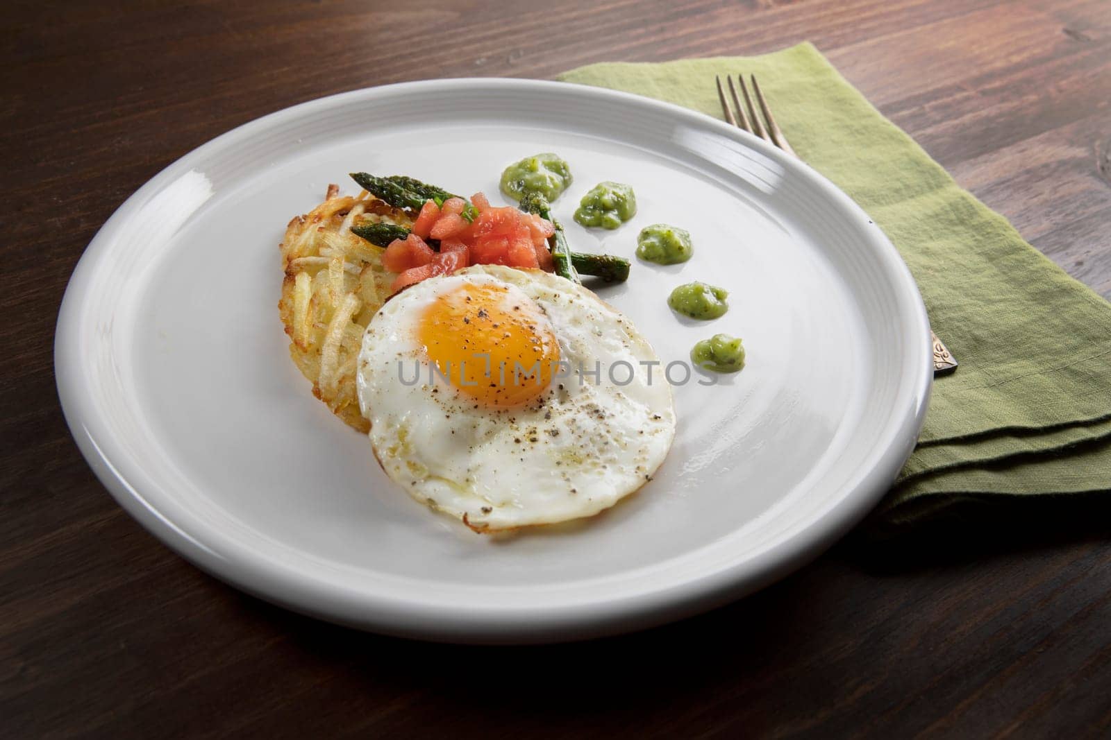 Fried egg with hashbrowns, asparagus, tomatoes and avocado sauce.
