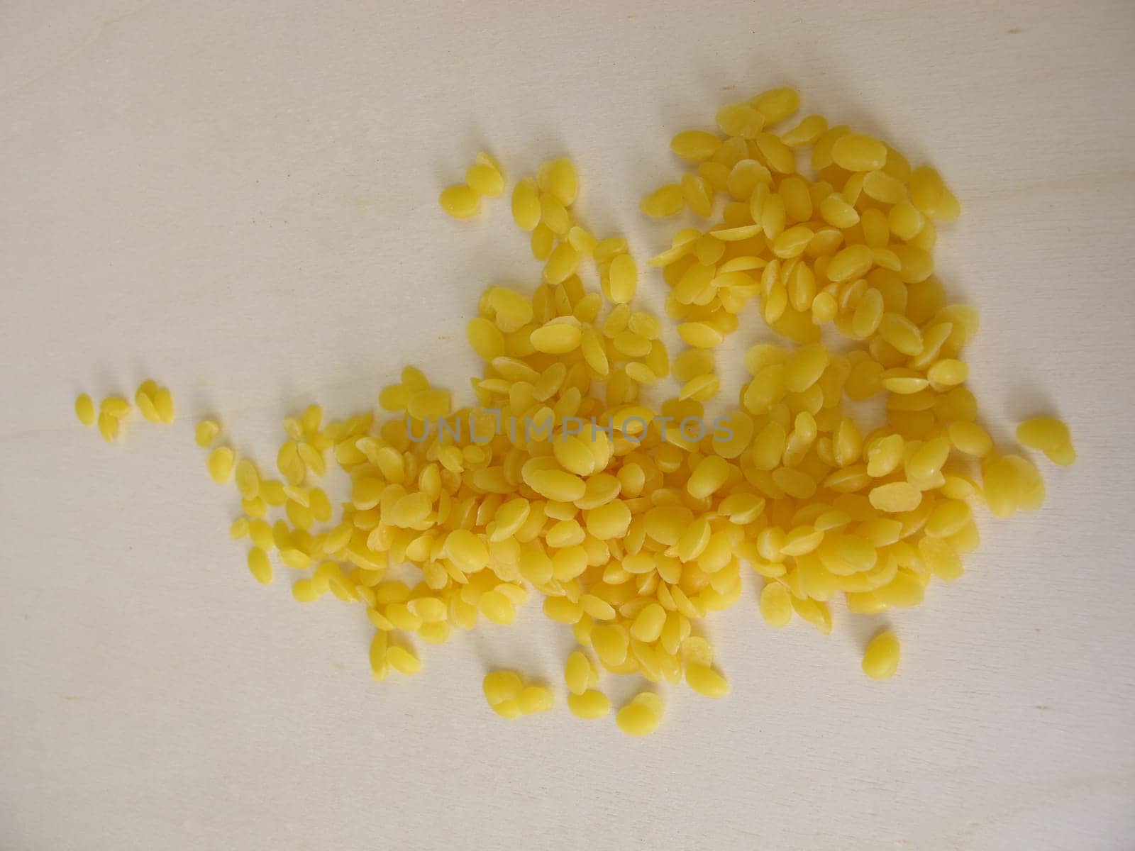 Pure beeswax pastilles for natural cosmetics, candles or beeswraps on wooden board