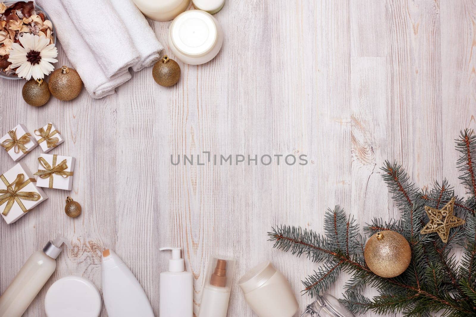 Spa still life with cosmetic creams, towel and Christmas ornaments on light wooden background. Top view with copy space. New Year and Christmas Healthy lifestyle, body care, Spa treatment
