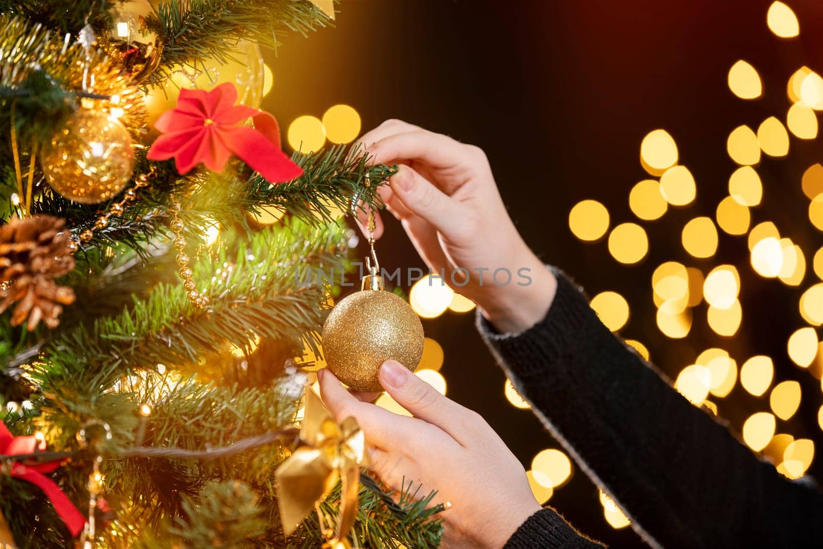 Girl decorates a Christmas tree. Closeup image of female hands decorating Christmas tree. Focus on her left hand!