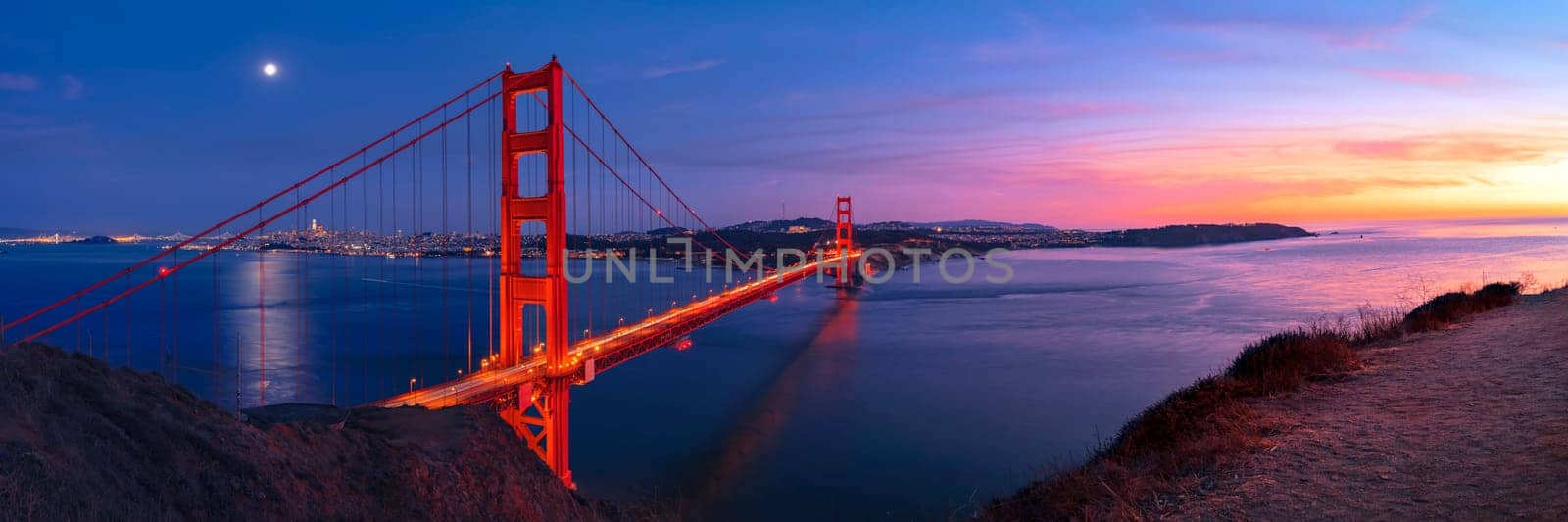 Golden Gate Bridge in San Francisco under full moon in sunset sky panorama