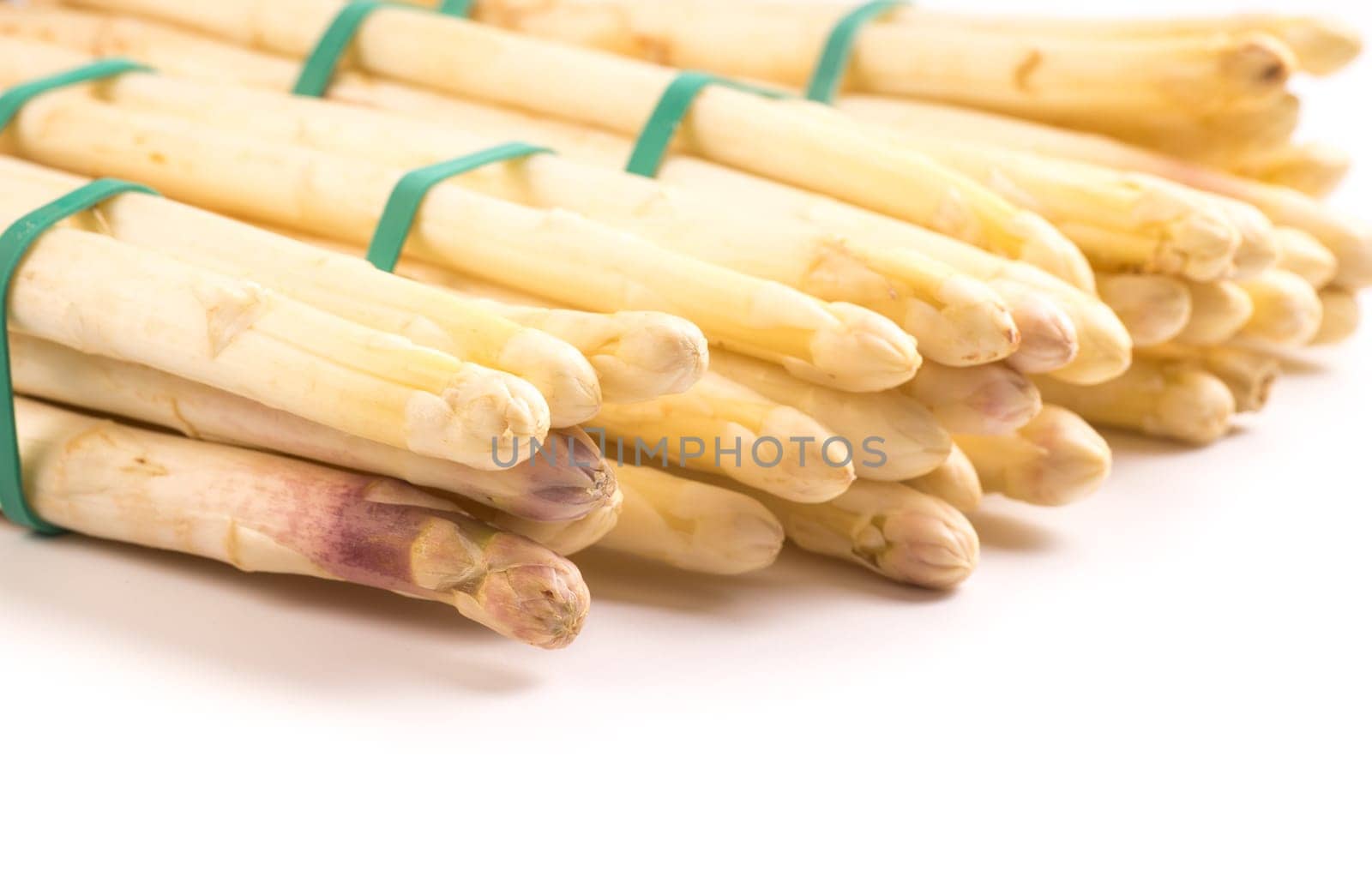 bundle of organic asparagus held together with green rubber bands isolated on white background