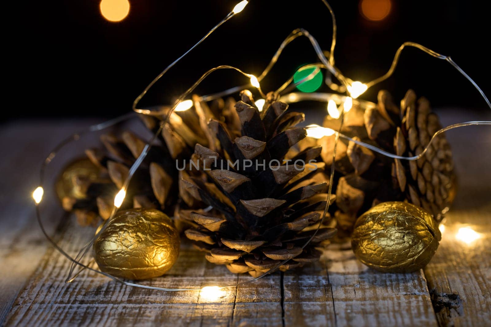 Composition of cones and painted walnuts with a garland of lpmpots and bokeh in the background