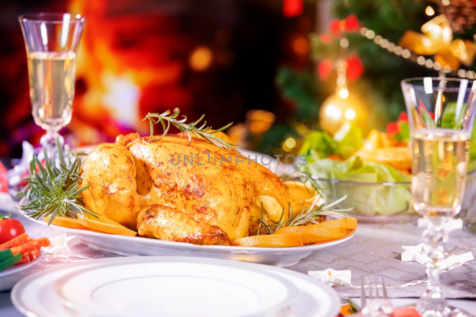 Christmas dinner. Chicken against glowing Christmas lights and burning candles. Holiday decorated table, Christmas tree, champagne and roasted turkey, Christmas served table. Focus on chicken!