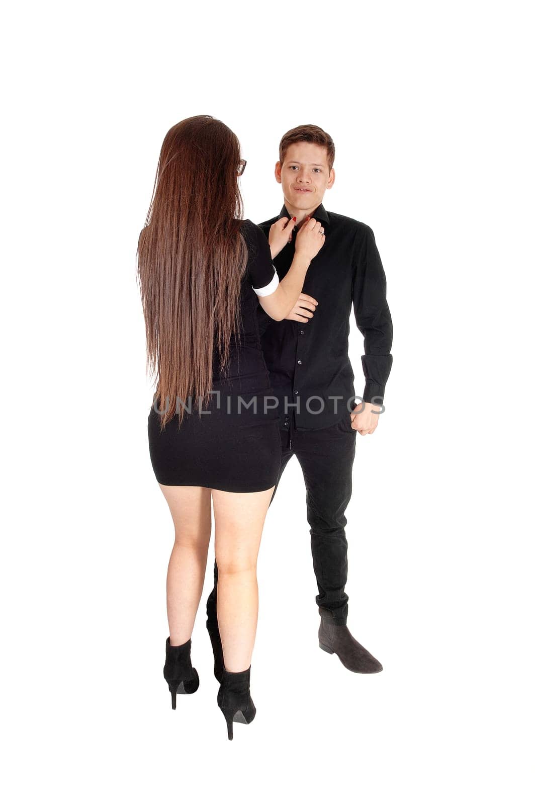 A young girl standing from the back fixing the tie of her brother, isolated.for white background.