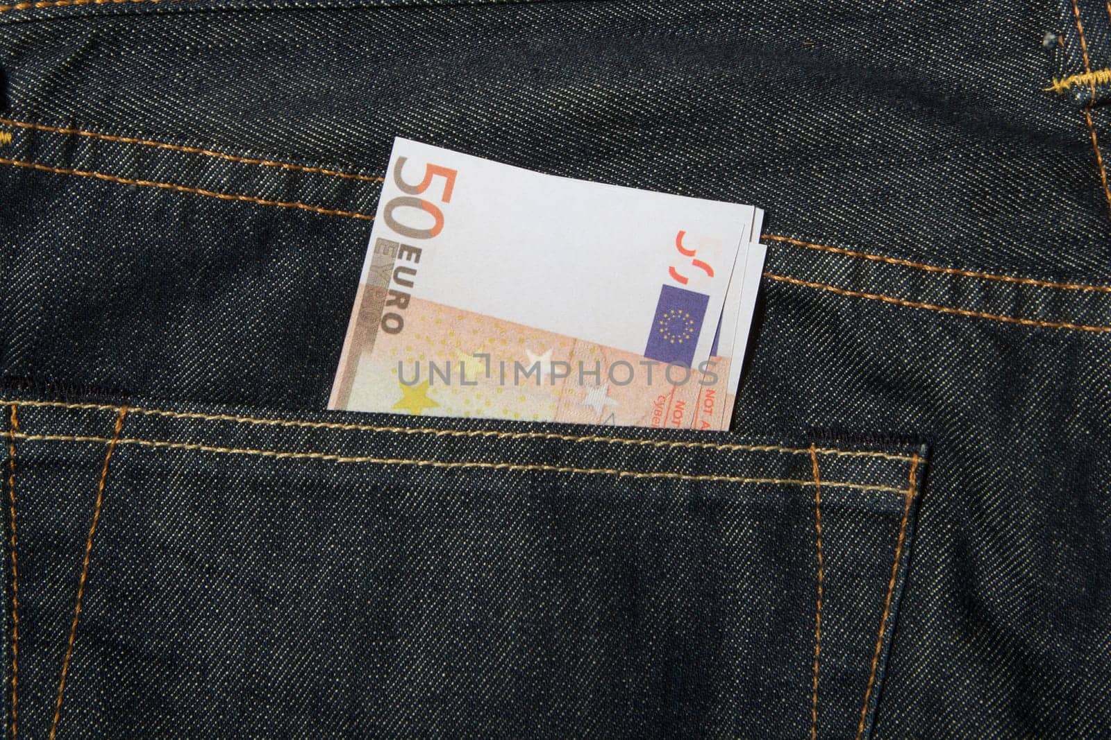 Euro banknotes in dark blue jeans back pocket.