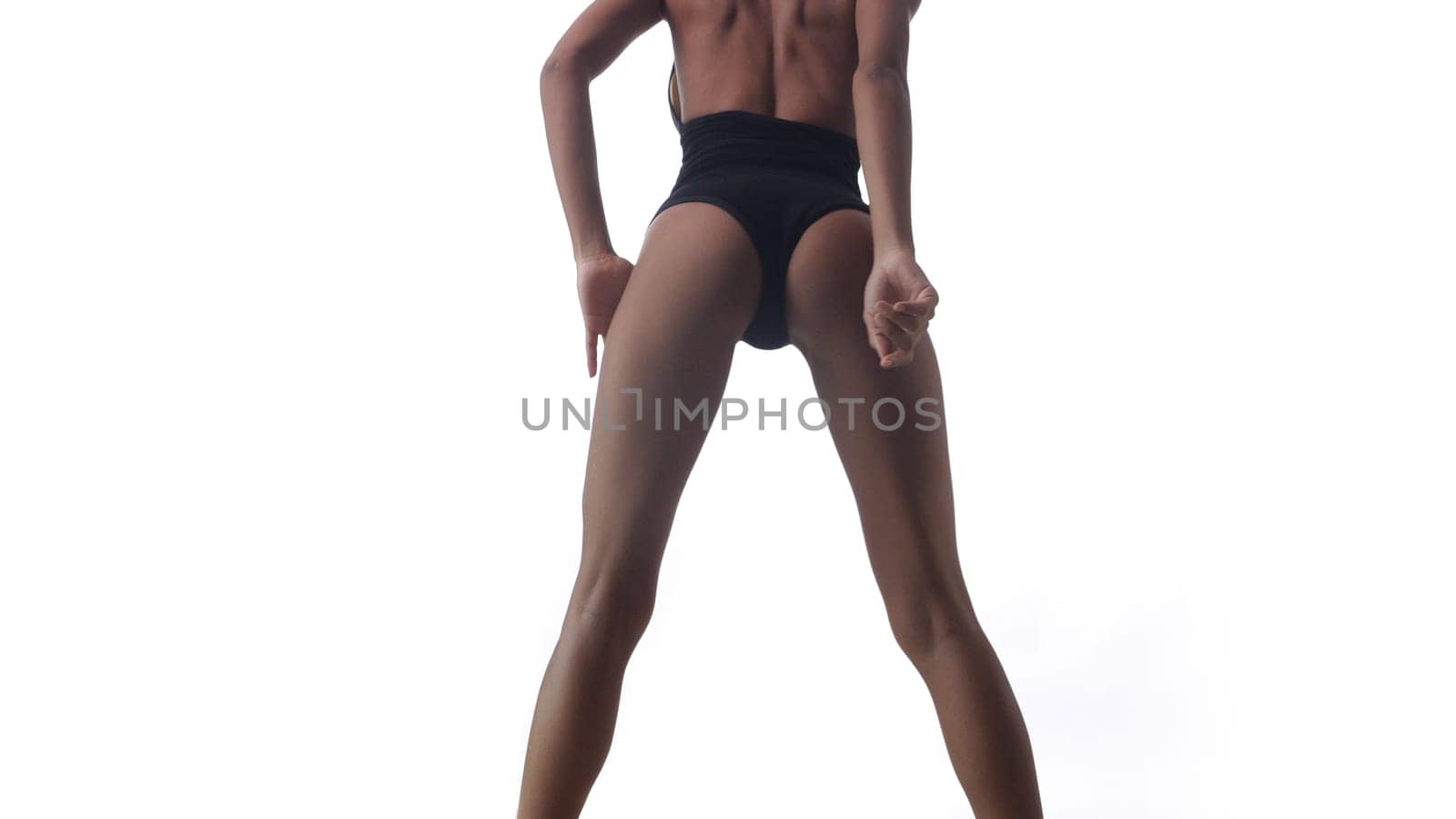Back view of beautiful woman in black bodysuit posing over white wall background