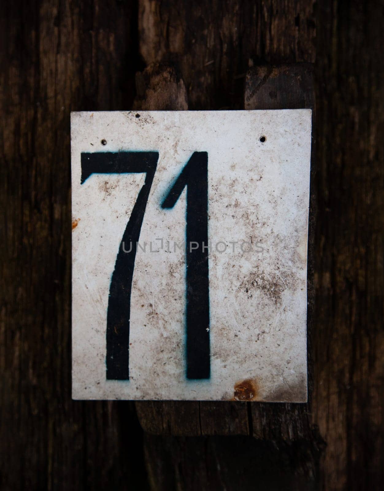 Number 12 is inscribed on a white metal plaque on a wooden background close up