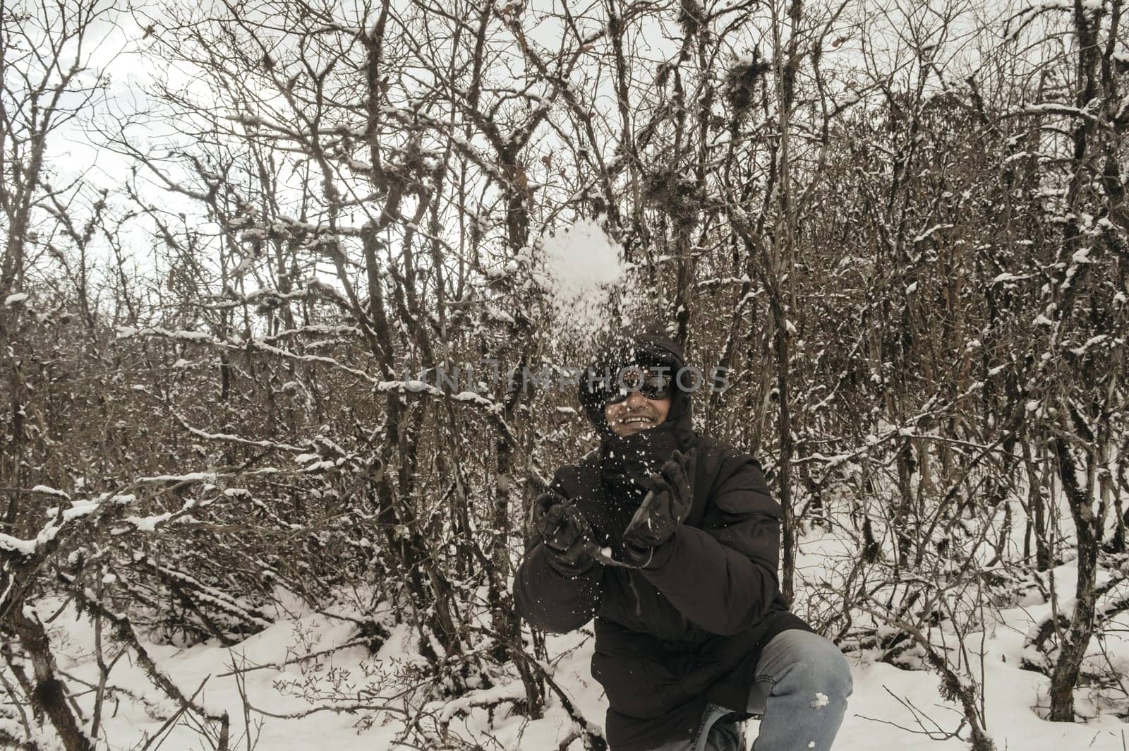 Smiling happy joyful Portrait of a Man wearing a black pullover jacket enjoying first snow playing and throwing snowball in air. Enjoy Snowing day view in winter. Rural village Jammu and Kashmir India