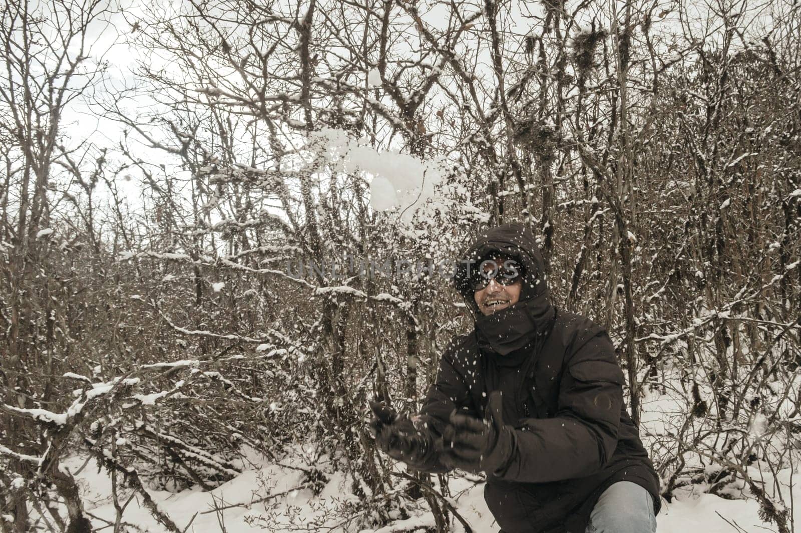 Smiling happy joyful Portrait of a Man wearing a black pullover jacket enjoying first snow playing and throwing snowball in air. Enjoy Snowing day view in winter. Rural village Jammu and Kashmir India