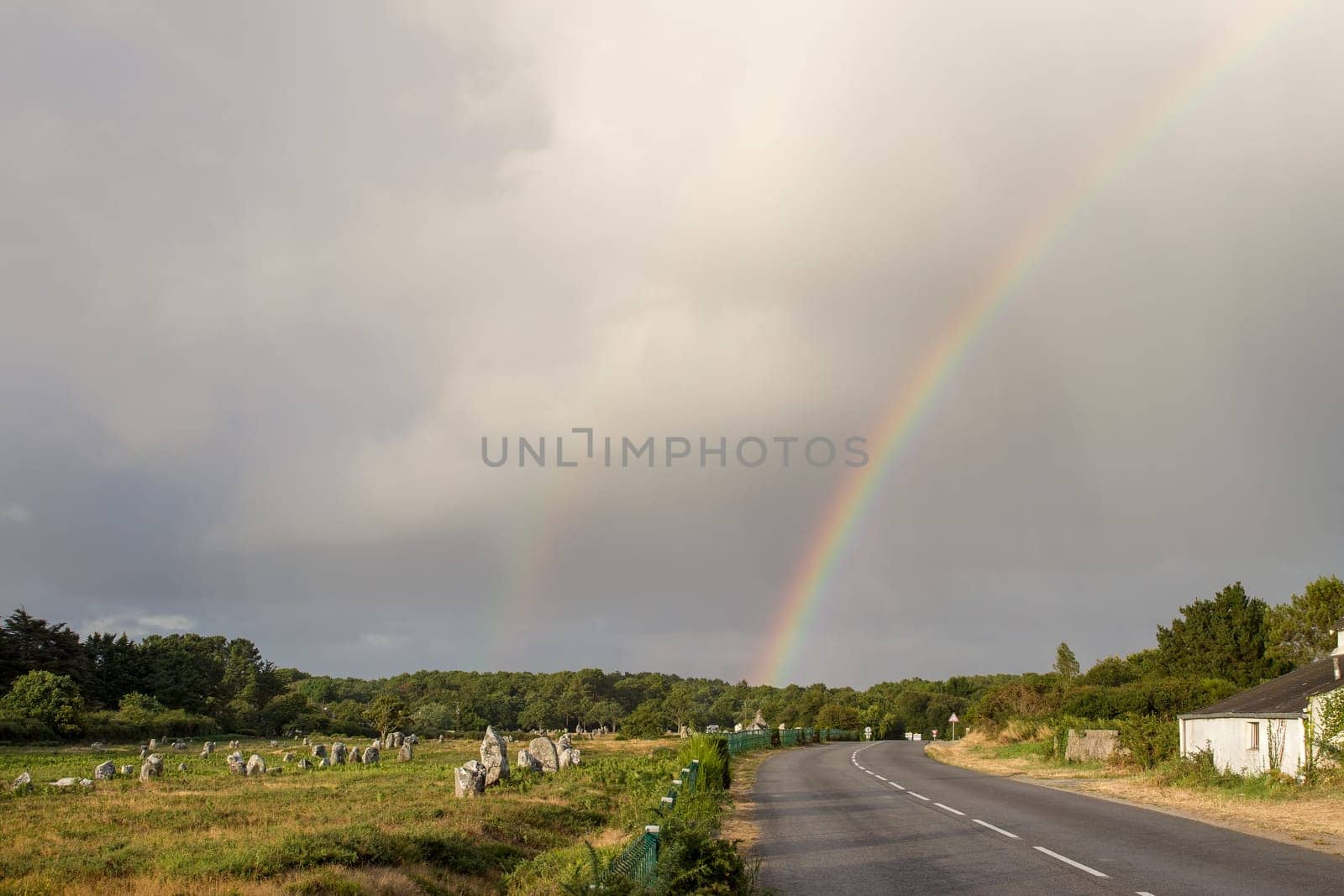 Rainbow over Alignments of Menec - rows of Menhirs - standing stones - the largest megalithic site in the world near Carnac in Brittany, France.