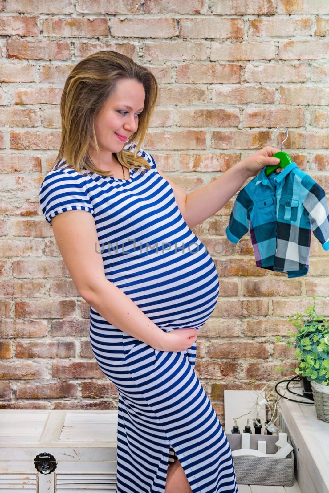 Beautiful pregnant woman sitting near brick wall
