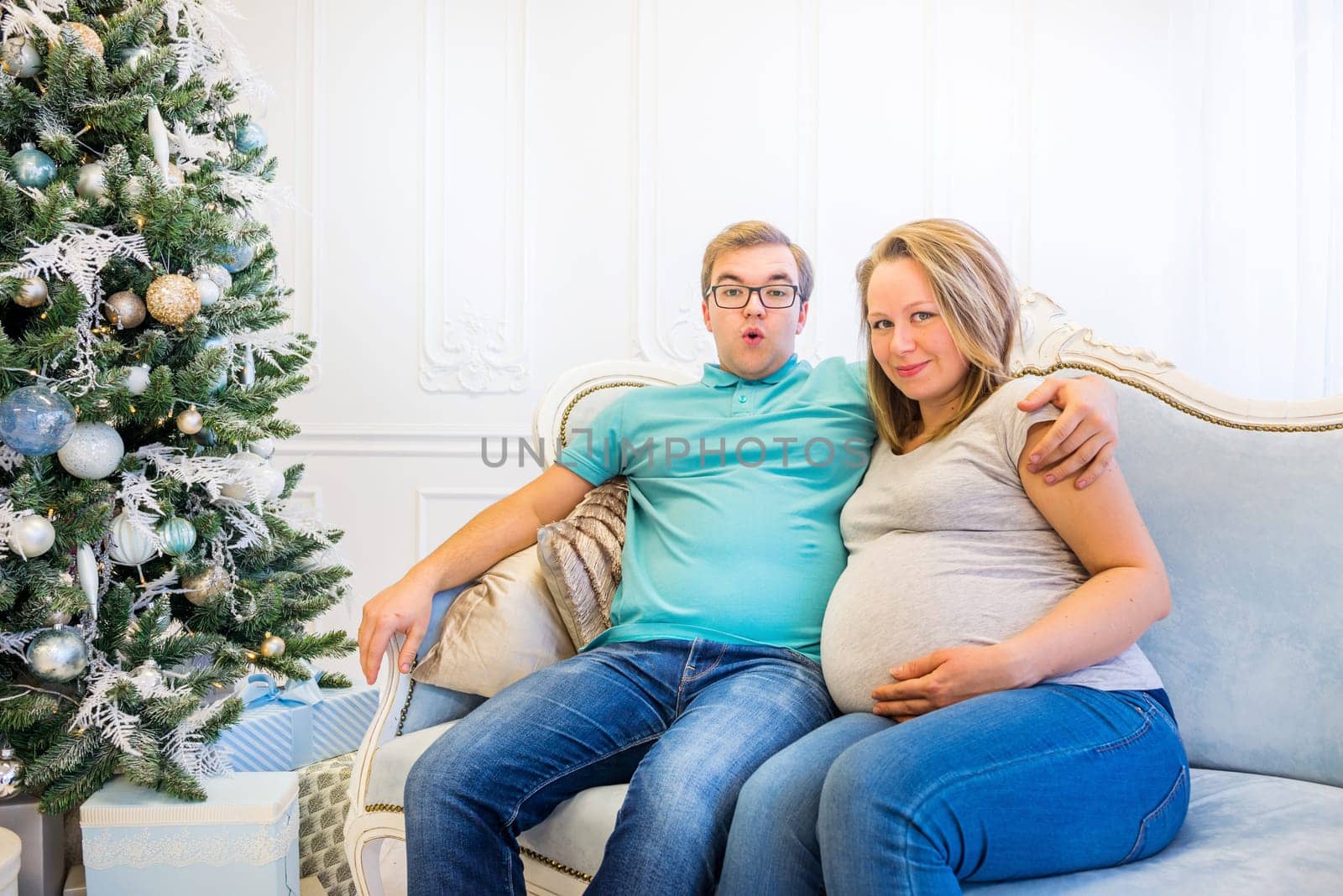 Family portrait near christmas tree. Pregnant woman.