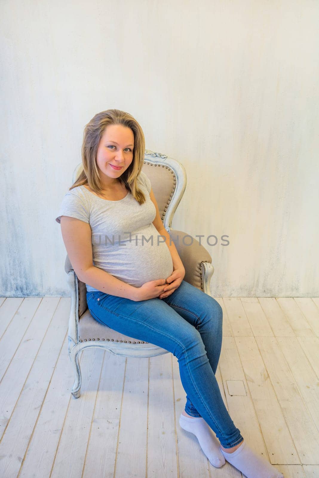 Beautiful pregnant woman sitting on the armchair