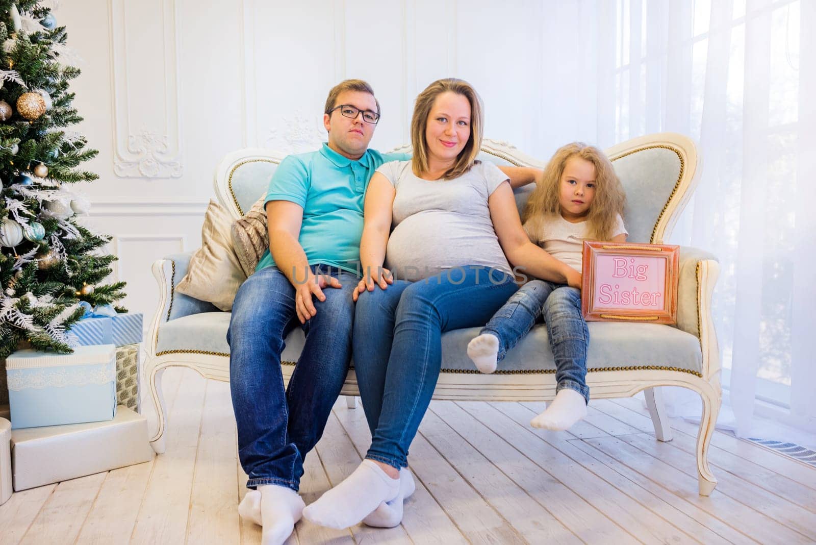 Family portrait near christmas tree. Pregnant woman