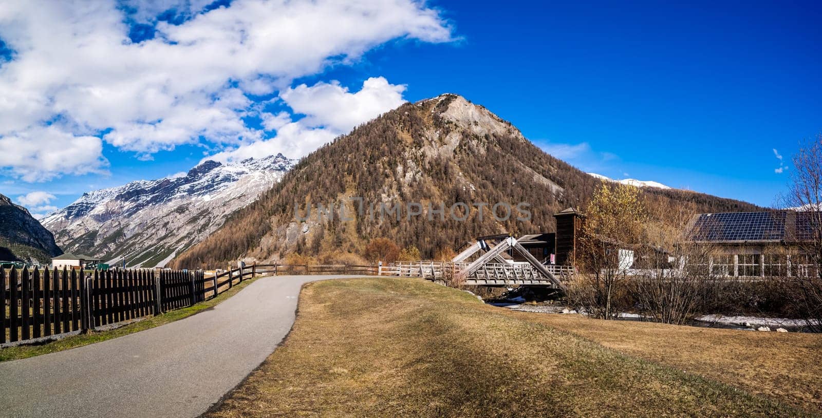 Beautiful panorama of mountain valley with stream, trees, footpath and wooden bridge, Livigno is a small town and ski centre for Italian Alps, Italy