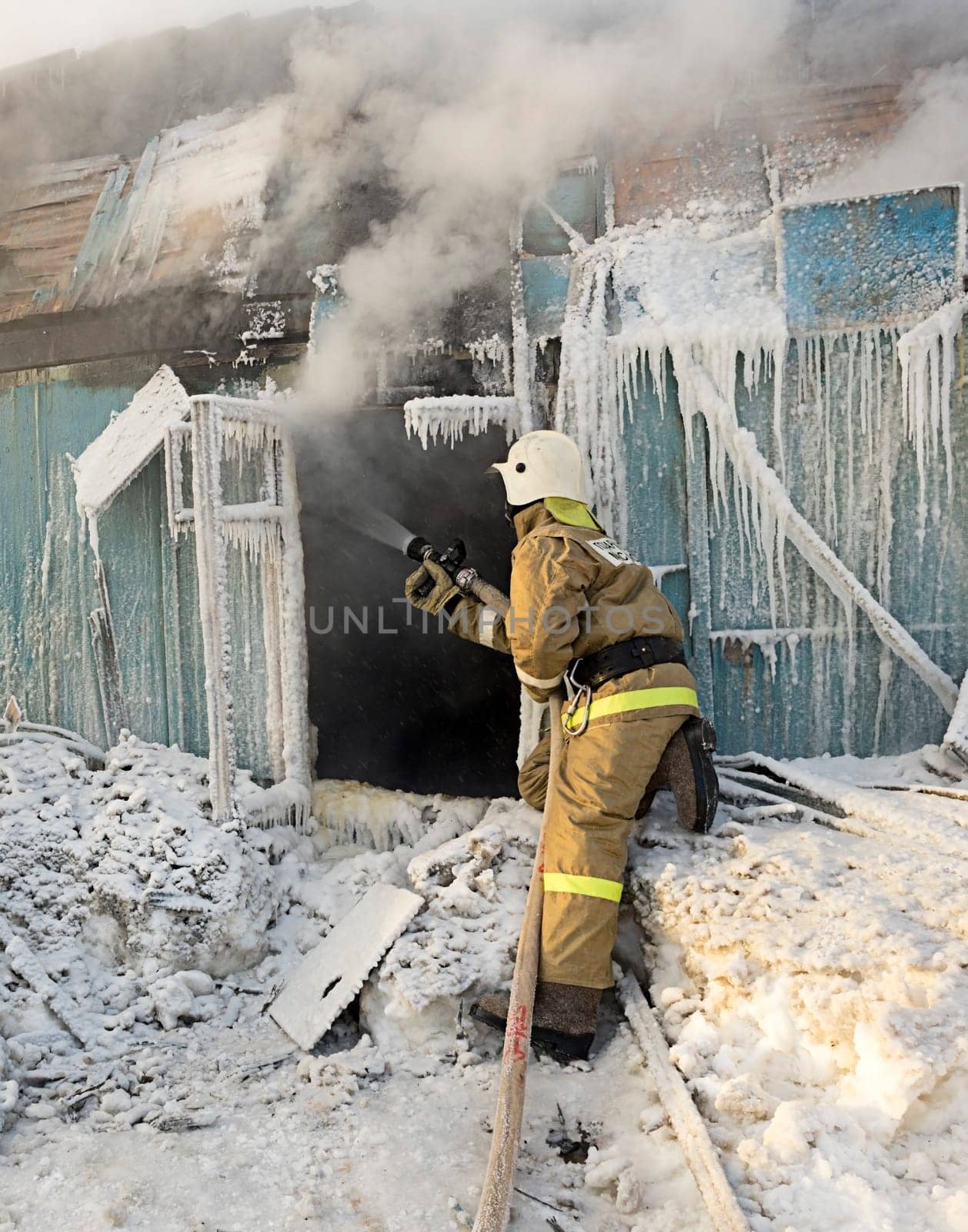 Firefighter extinguishes a fire in a wooden house