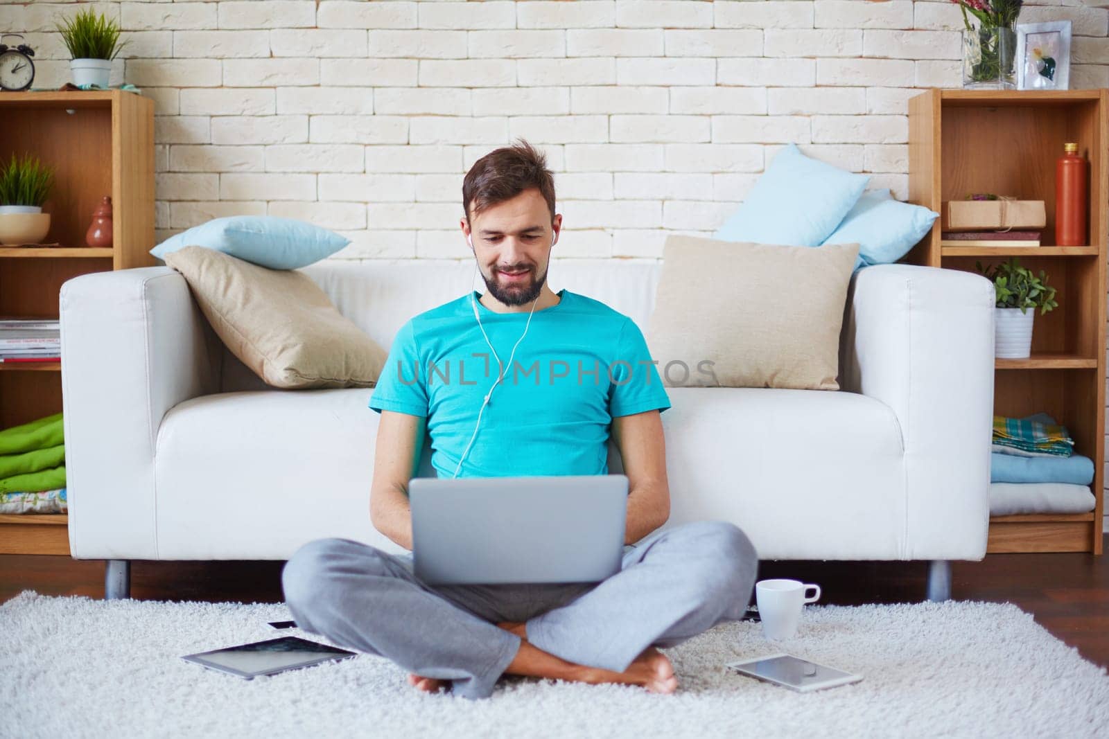 Handsome guy in casual clothes using modern gadgets at home