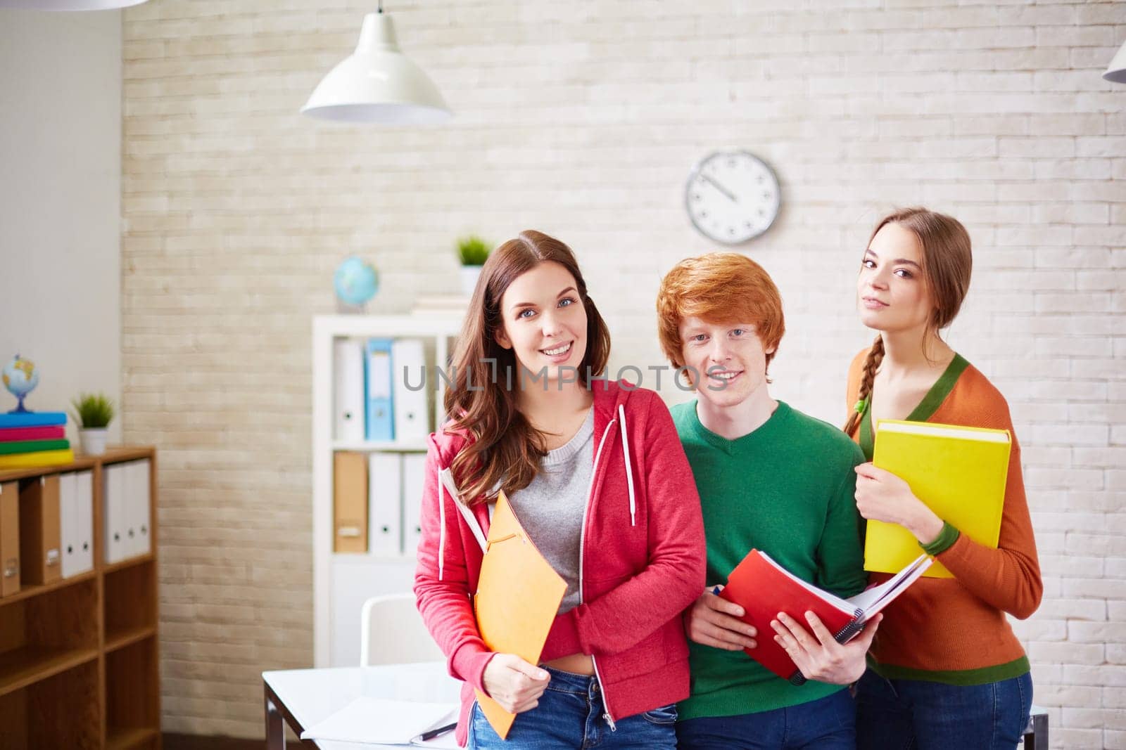 Group of students standing by desk in classroom