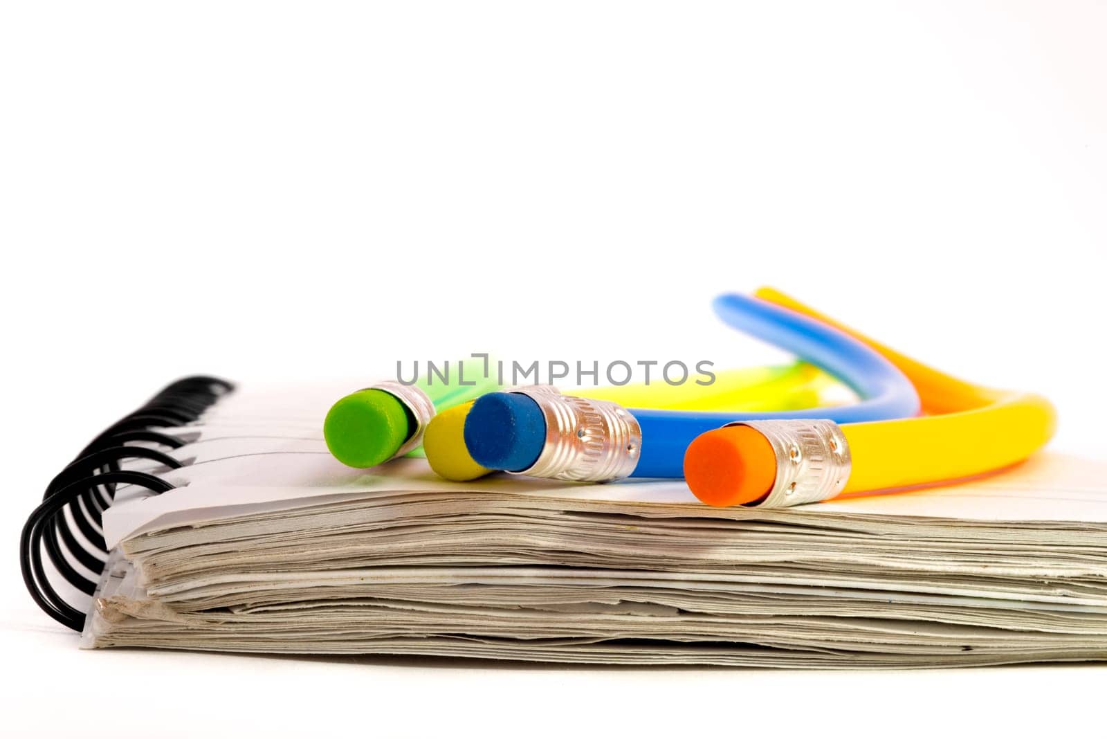 Four colourful pencils that are all strangely bend, lying on a notebook.