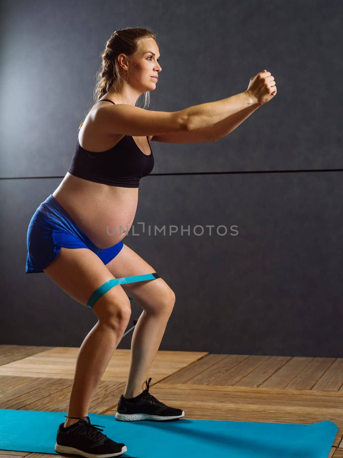 Pregnant woman in her thirties exercising with a resistance band.