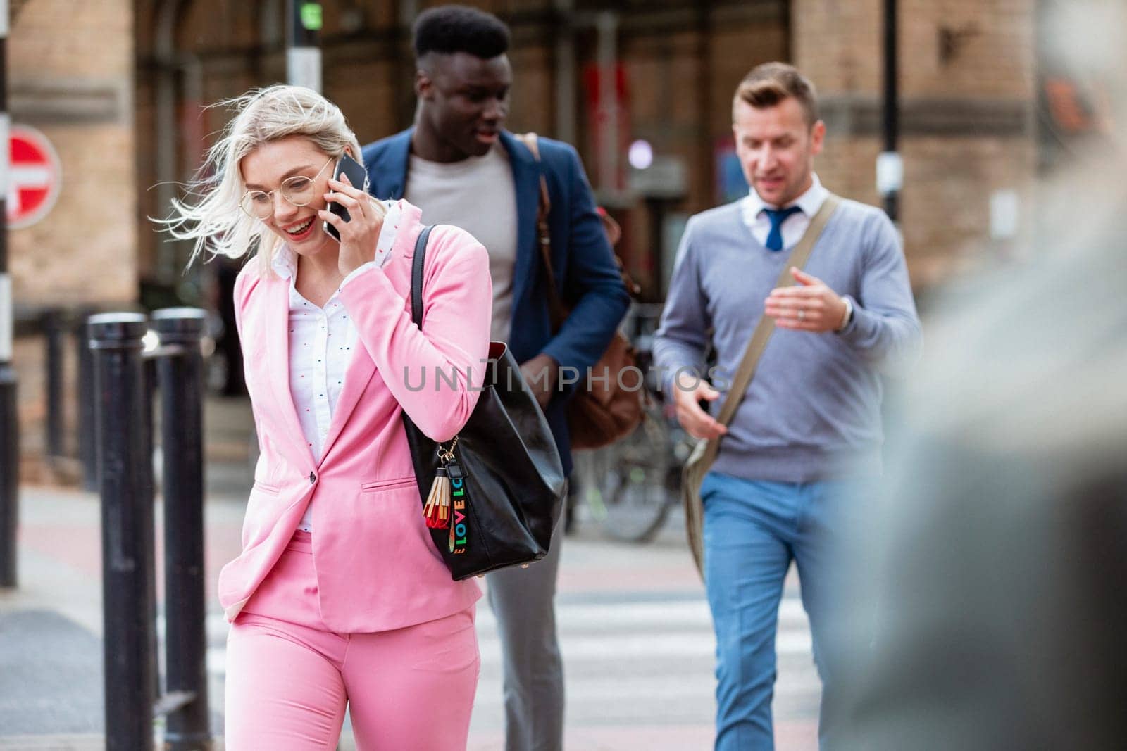 Businesspeople walking home after a day of work. The main focus is on one businesswoman walking in front of people while talking on her mobile phone.