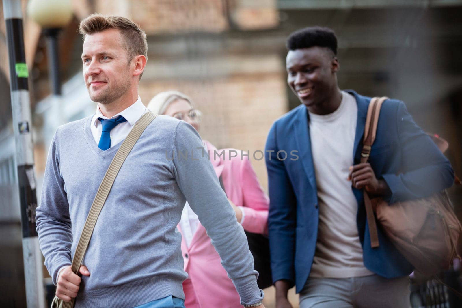 Businesspeople walking home after a day of work. The main focus is on one man walking in front of people.