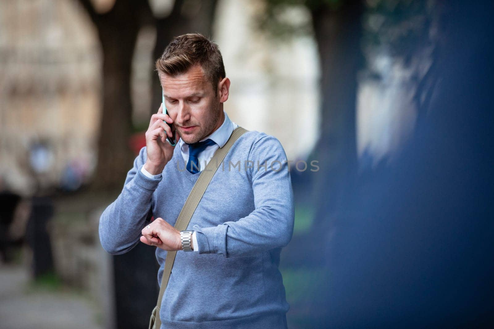Businessman on his way to work while talking on the phone and checking the time.