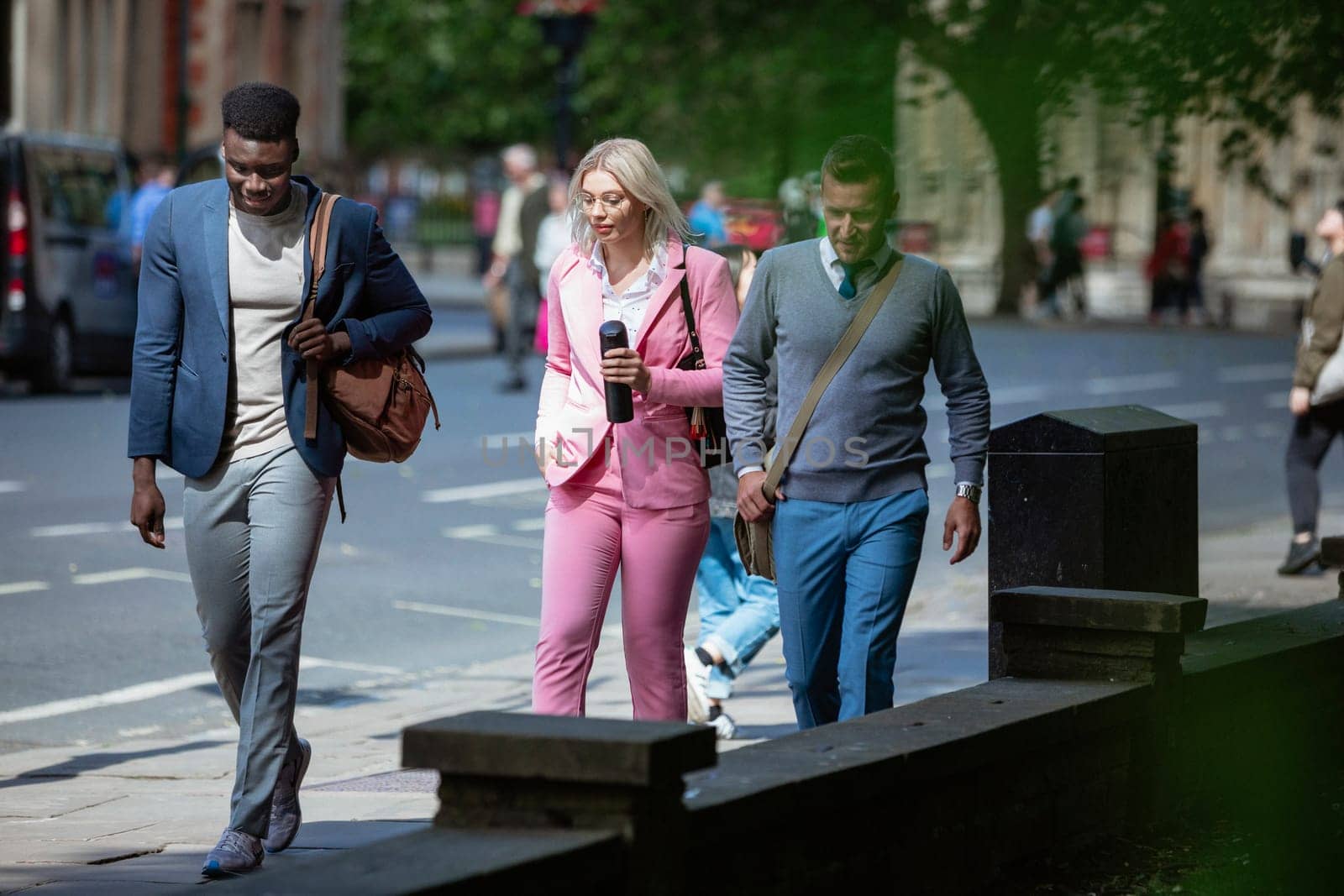 A businesswoman is walking with two businessmen to work through the city.