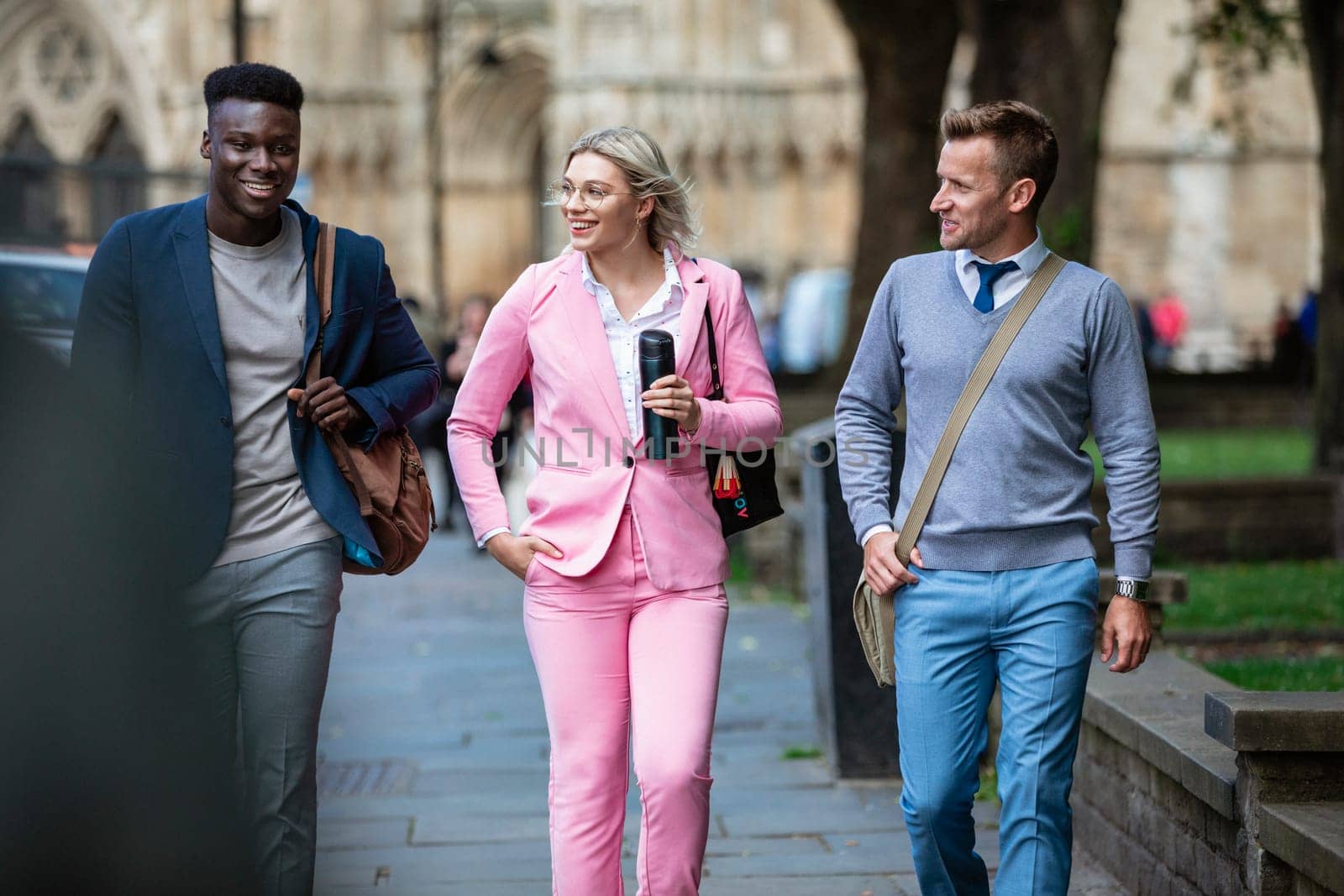 A businesswoman is walking with two businessmen to work through the city.