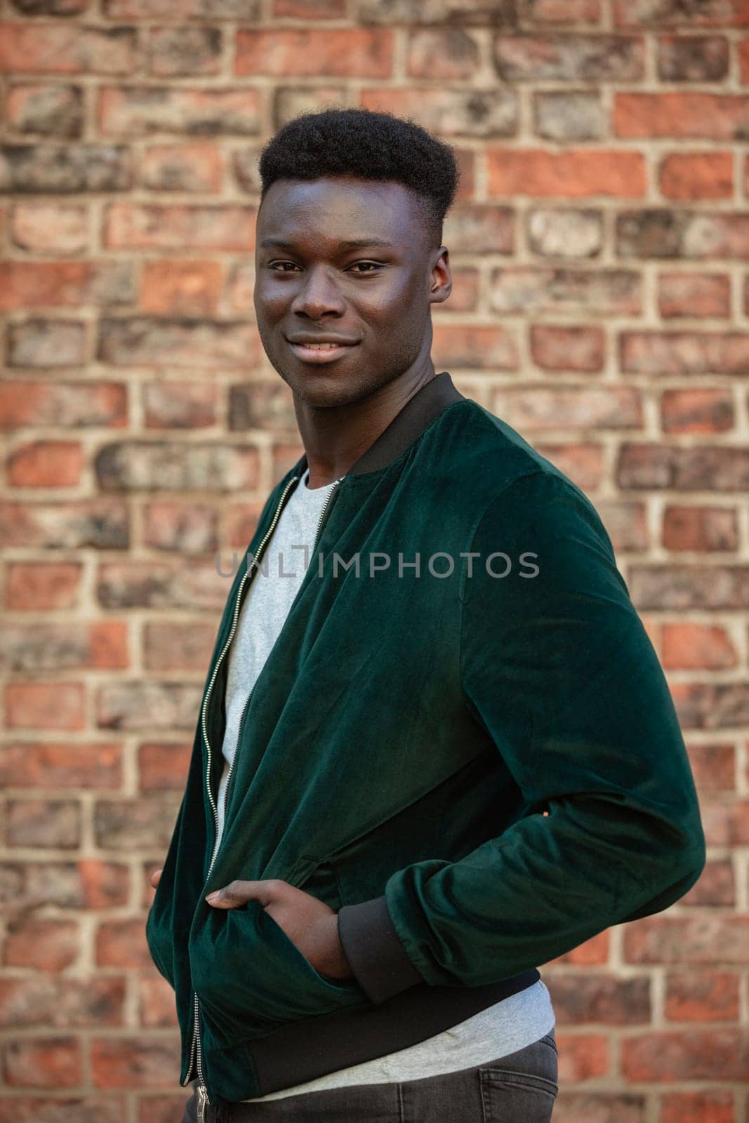 A man standing on his side while looking into the camera and smiling.