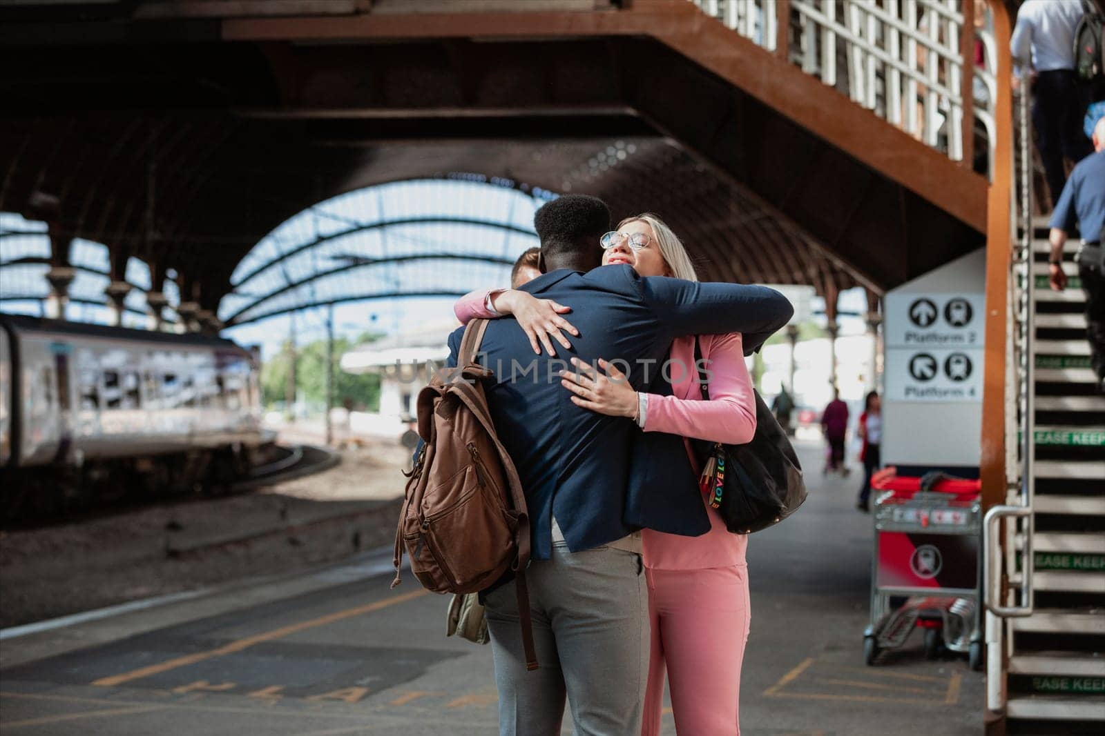A male and female co-worker parting ways after work. They are hugging each other goodbye.