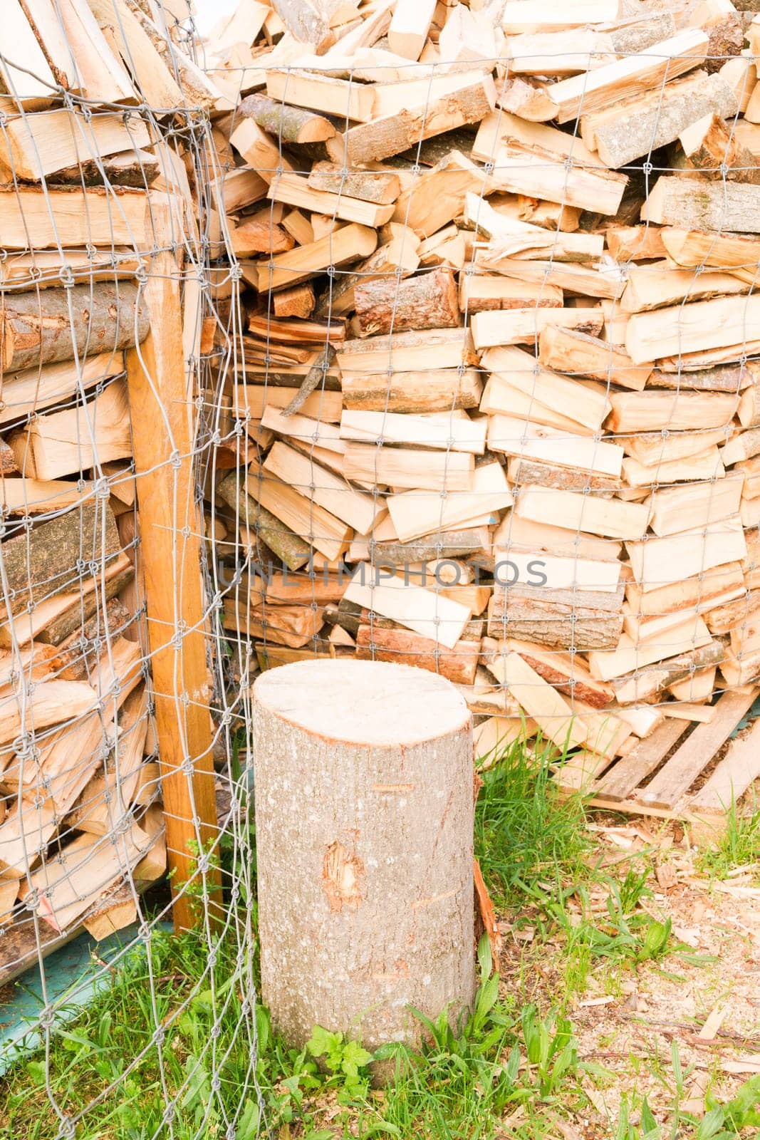 Logs in a metal grid cage with a chopping block on a lumber yard