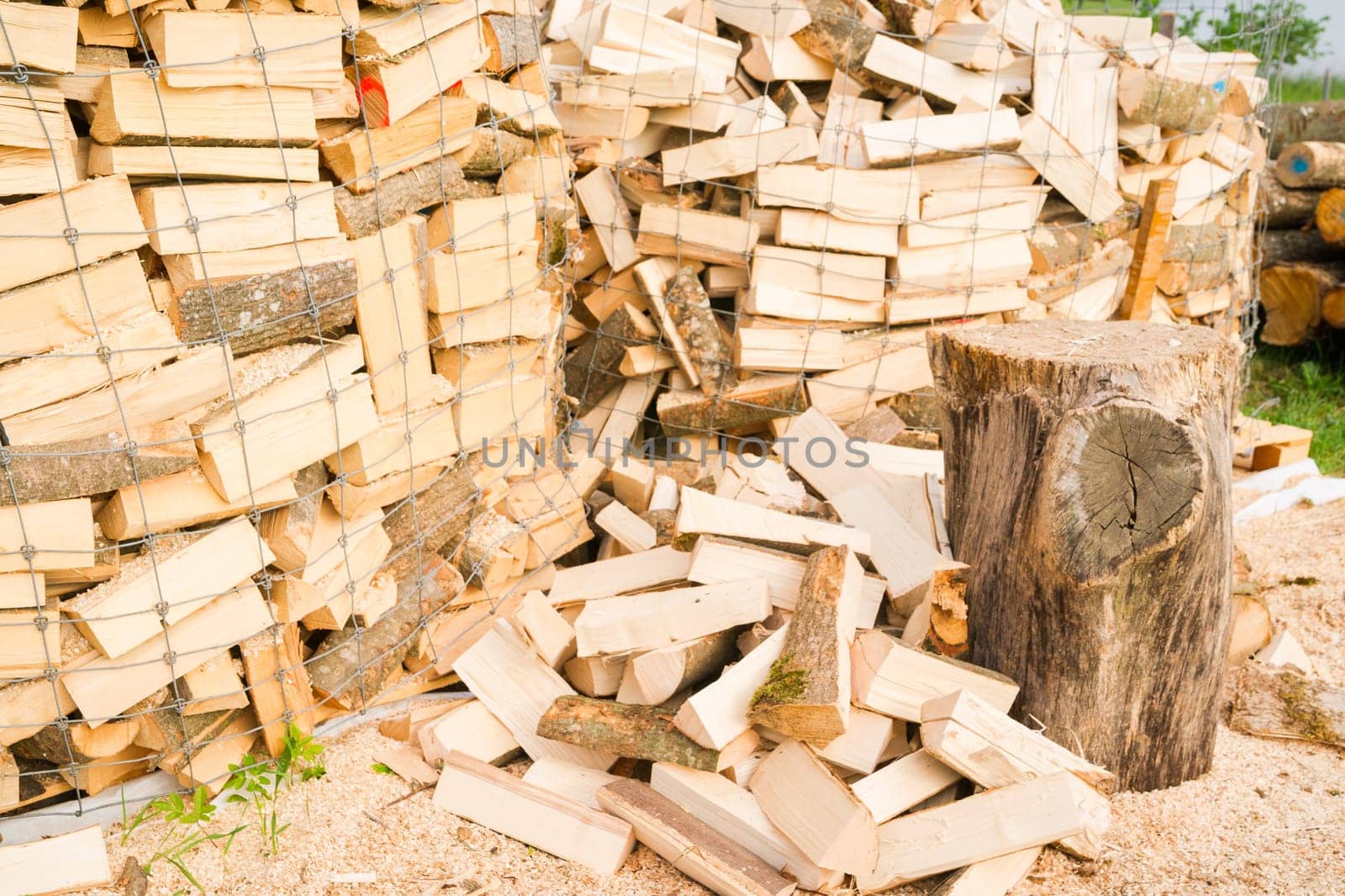 Logs in a metal grid cage with a chopping block on a lumber yard