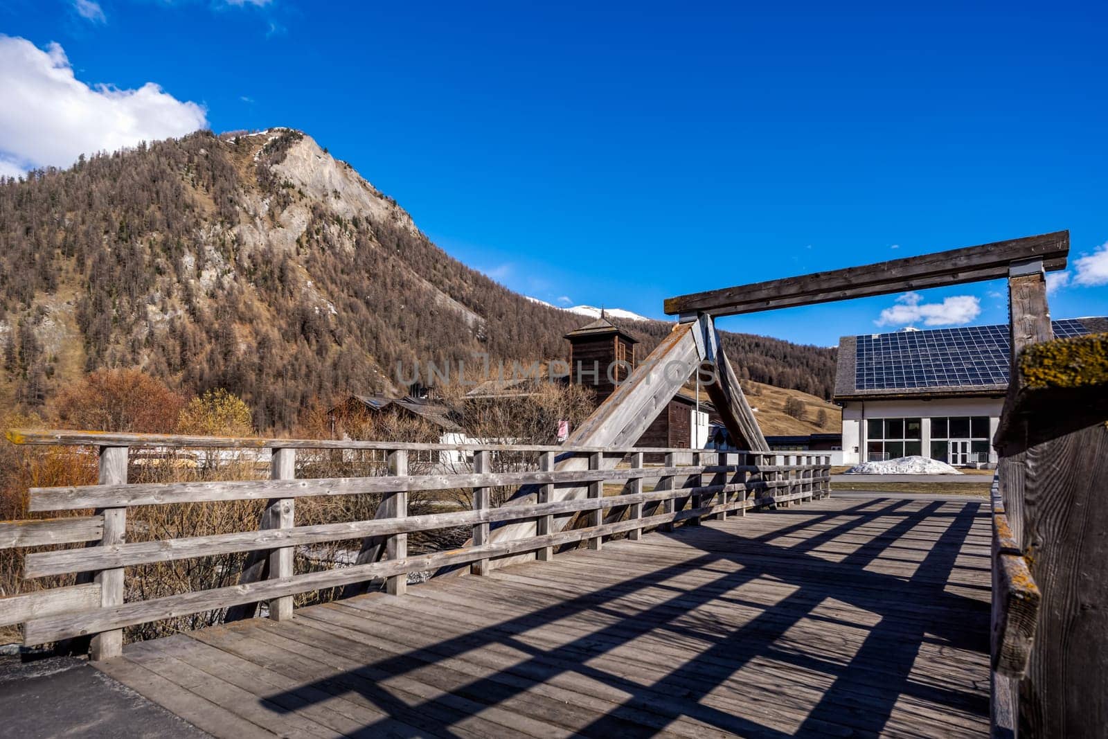 Beautiful mountain valley with stream, trees, footpath and wooden bridge, Livigno is a small town and ski centre for Italian Alps, Italy