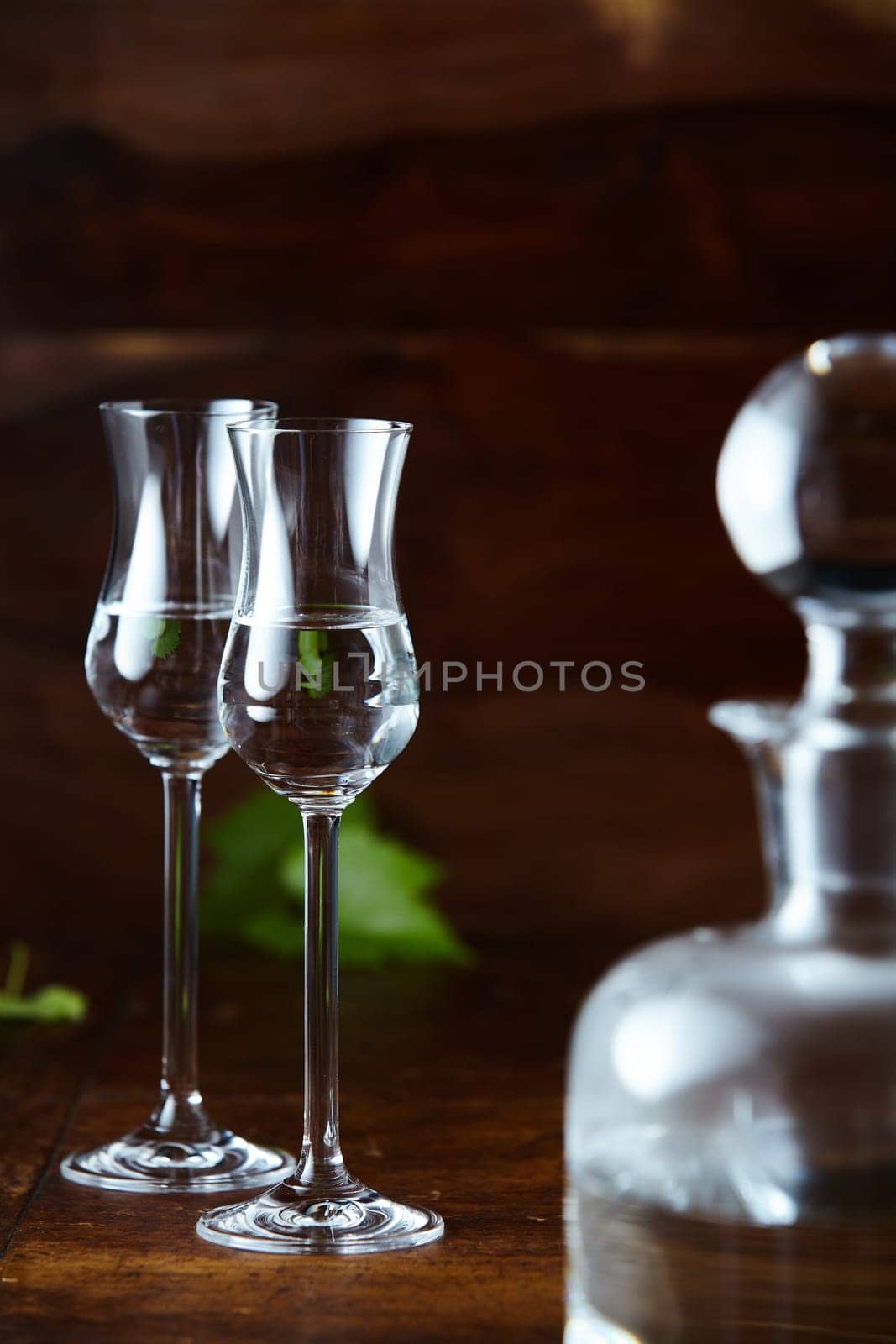 Two elegant tulip glasses of grappa and glass decanter blurred in foreground
