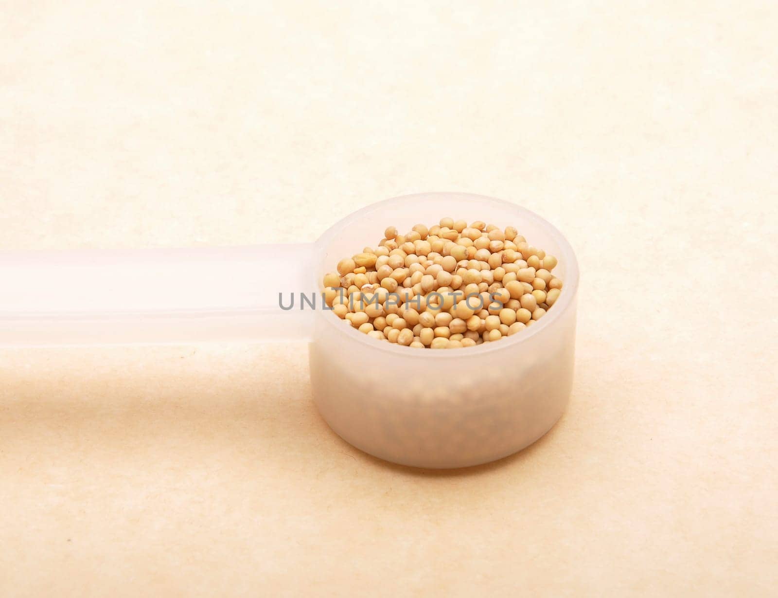 Mustard seeds in measuring spoon on brown background