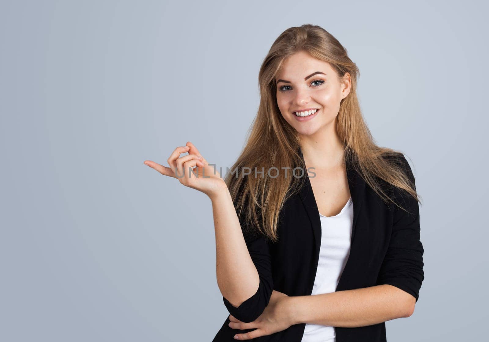 Blonde girl pointing aside, isolated on grey