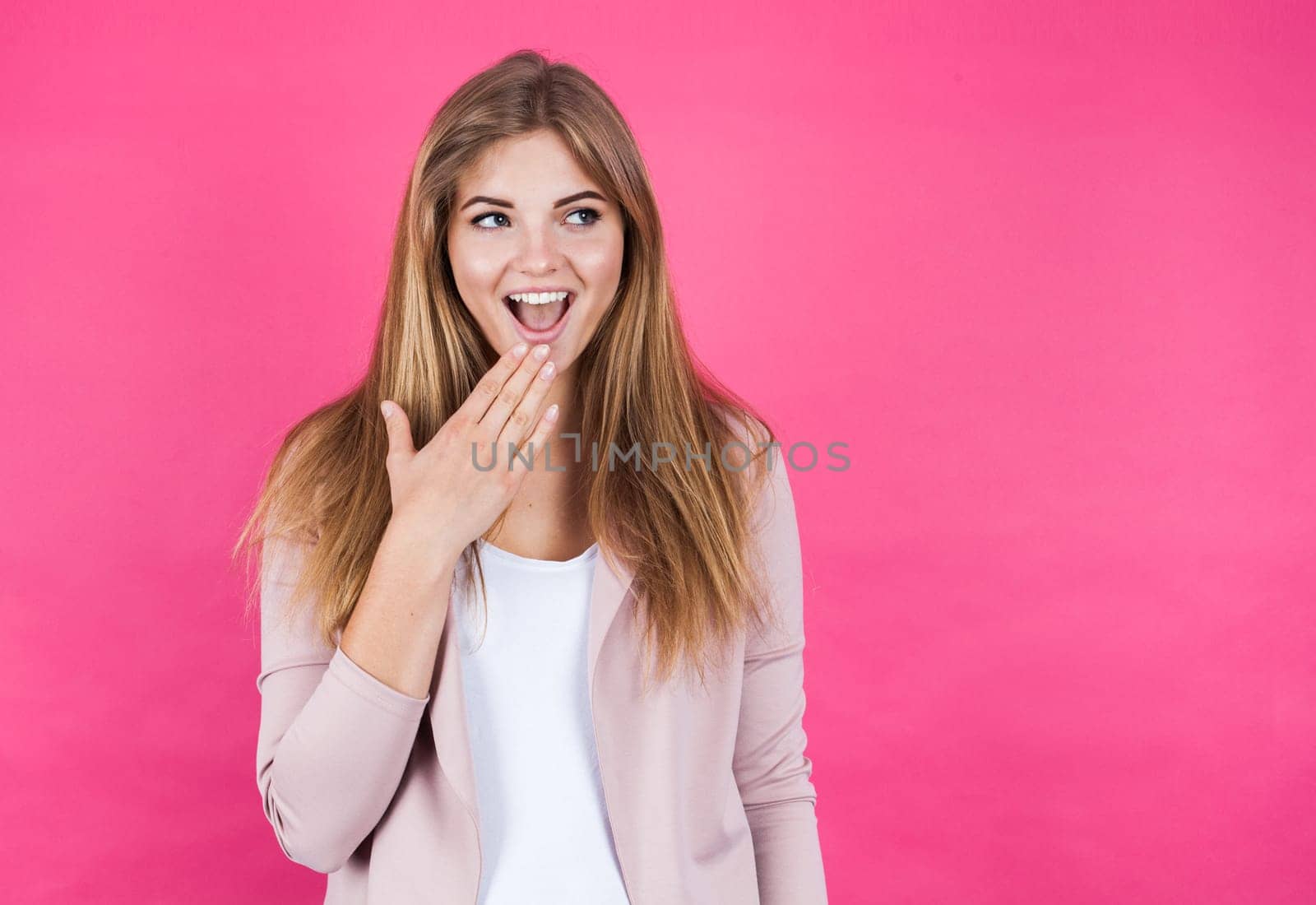 Young blonde girl astonished, isolated on pink background