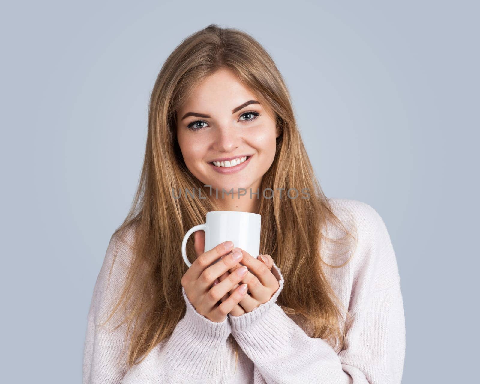 Portrait of a young beautiful woman holding a cup, isolated on grey
