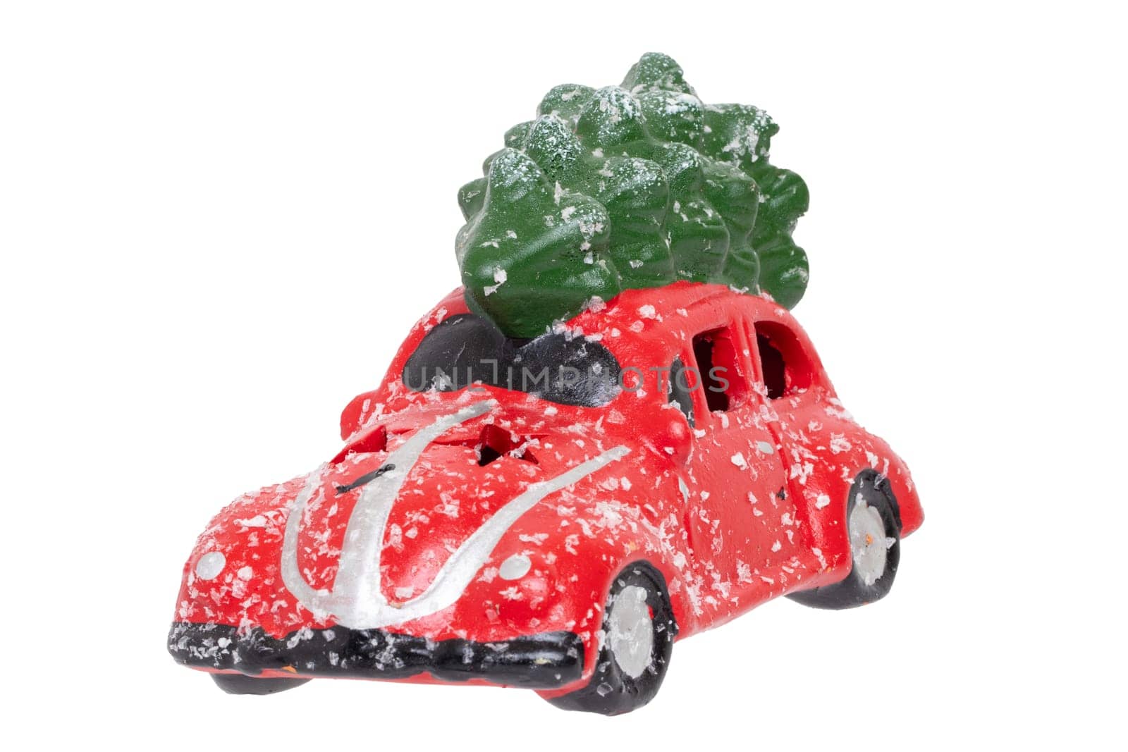 Christmas decorations background. Closeup of a snow-covered red car toy with green fir-tree on the roof isolated on a white background. Saisonal design element for cards or stickers. Macro.