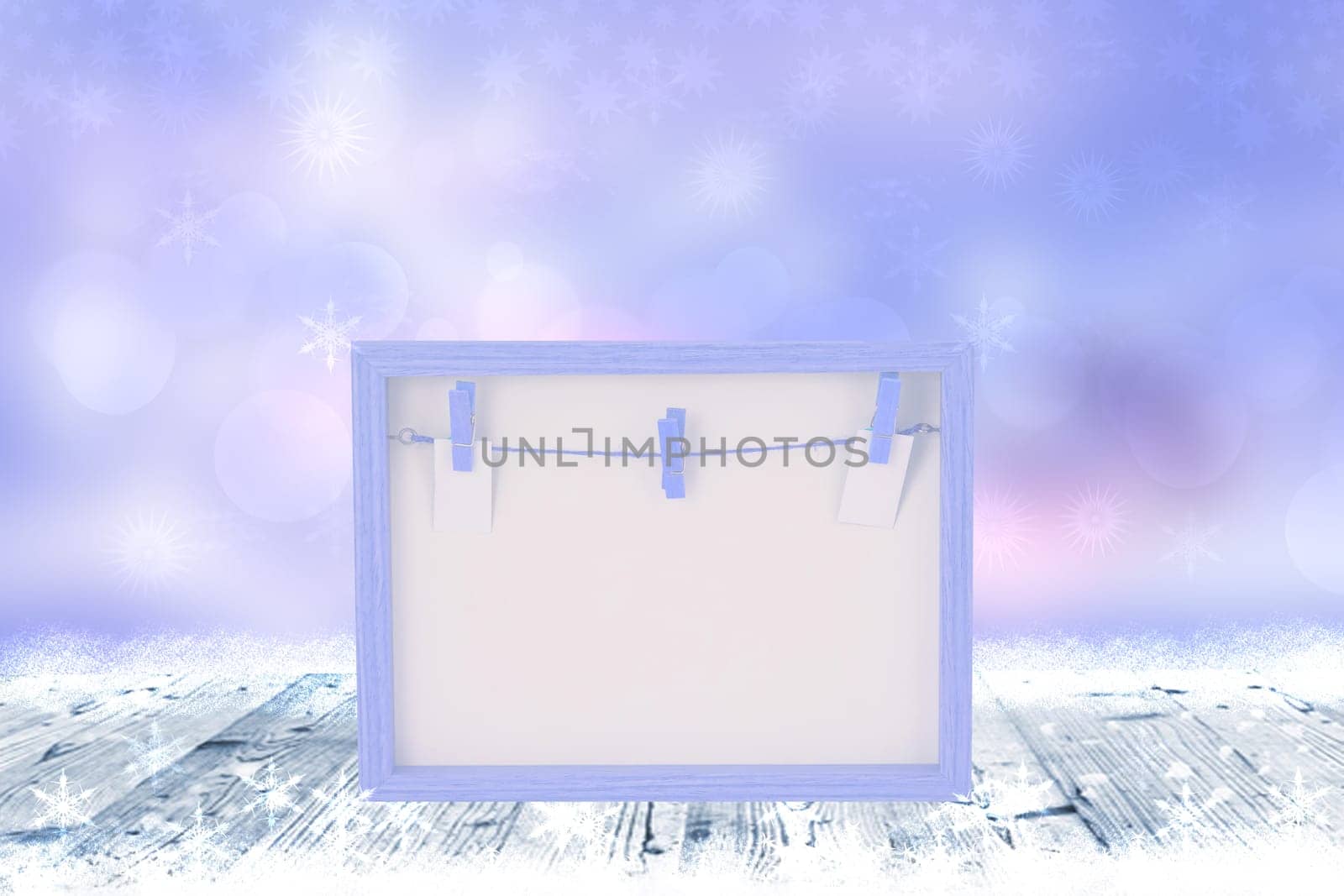 Empty pink wooden frame with a clothesline and clothespins on a rustic wooden table with snow over abstract winter christmas or other holidays background. Space for design. Card concept.