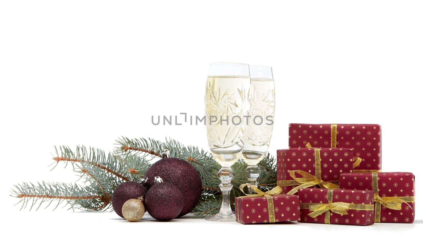 Still life with two champagne flutes, gift boxes and Christmas decoration with fir tree branch isolated on white background with copy space. Christmas and New Year shopping. Greeting card