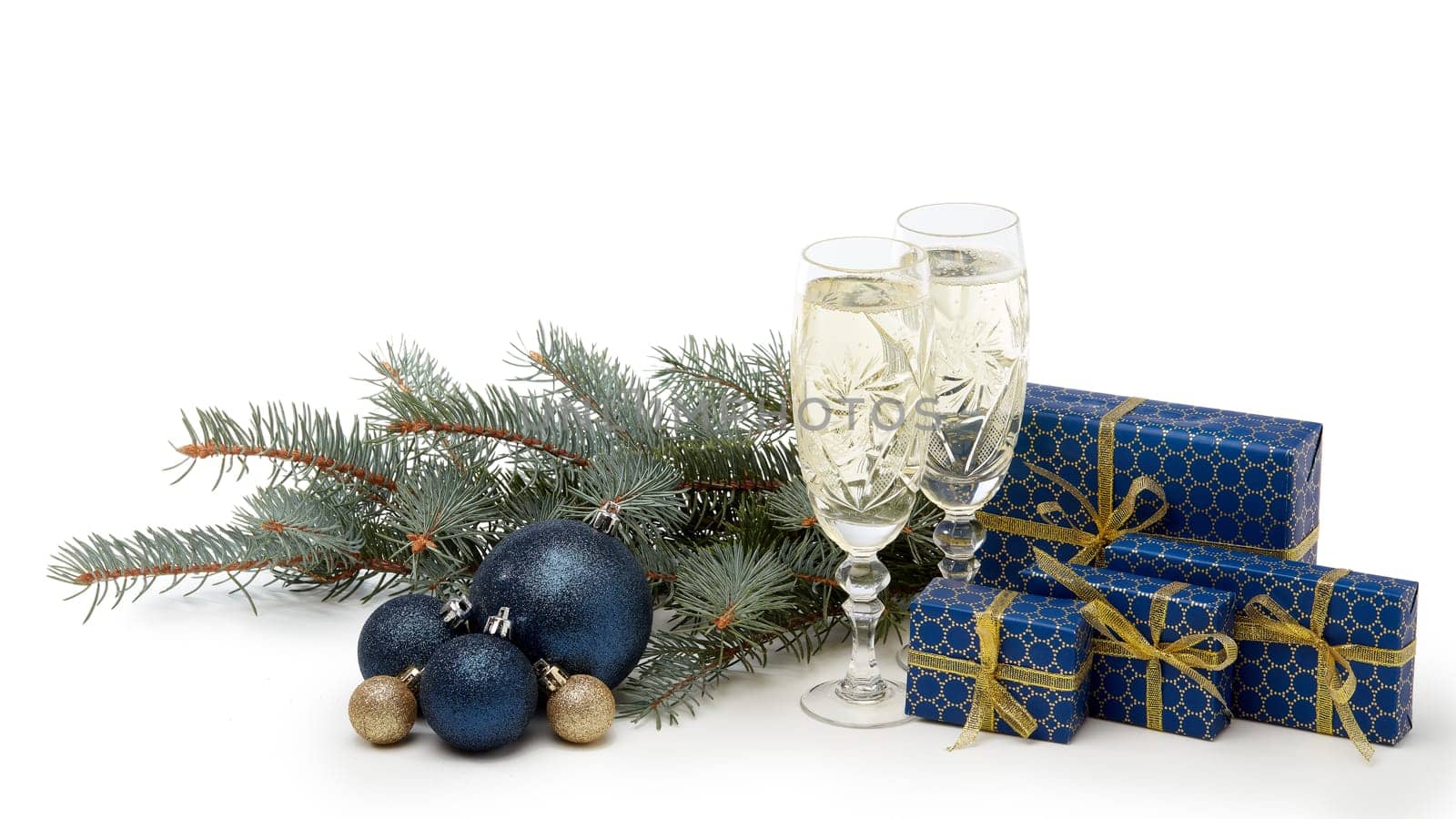 Still life with two champagne flutes, gift boxes and Christmas decoration with fir tree branch isolated on white background with copy space. Christmas and New Year shopping. Greeting card